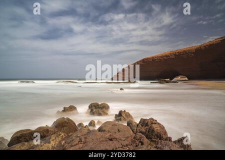 Eine Langzeitaufnahme des Strandes und des Felsenbogens bei Legzira an der Atlantikküste von Morroco Stockfoto
