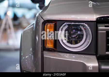 Das Bild zeigt eine detaillierte Nahaufnahme des Scheinwerfers eines schlanken, glänzenden Autos und zeigt sein Design und seine Beleuchtungsmerkmale Stockfoto
