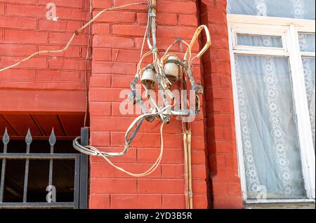 Elektrische Betriebsmittel und Hochspannungsleitungen an der Wand Stockfoto