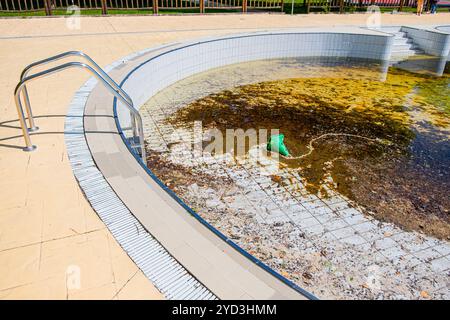 Schmutzige Poolwasseroberfläche mit Herbstblättern, die auf dem Wasser schwimmen. Stockfoto