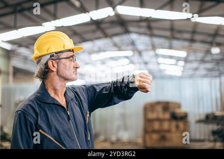 Ein leitender Arbeiter, der auf eine Uhr auf seiner Armbanduhr blickt und die Arbeitszeiten der Mittagsbremse wartet. Stockfoto