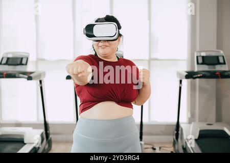 Frau, die das VR-Headset für das Training im modernen Fitnessstudio verwendet. Fitness, Technik und Motivationskonzept. Stockfoto