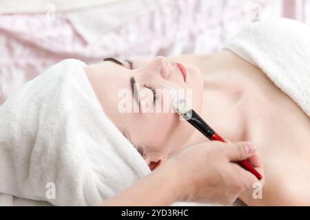 Kosmetikerin Kosmetikerin wendet Kräutercreme Maske mit Spatel an, professionelles Verfahren in einer Schönheitsklinik Salon für Kunden. Hautpflege und Kosmetologie Stockfoto