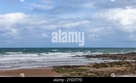 Strandhill Beach in Irland bietet eine zerklüftete felsige Küste mit Wellen und nassem Sand unter einem hellblauen Himmel mit verstreuten Wolken Stockfoto