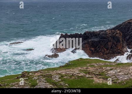 Wellen des Atlantiks prallen gegen die strukturierten, zerklüfteten Felsen der irischen Küste und schaffen eine dramatische Küstenlandschaft Stockfoto