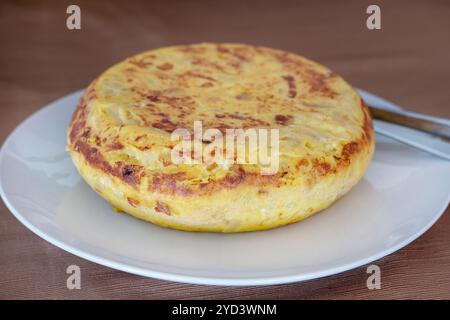 Ganze klassische spanische Tortilla, bekannt als Tortilla de patatas, traditionelle Grundnahrungsspezialität aus einfachen Zutaten wie Kartoffeln, Zwiebeln und Eiern Stockfoto