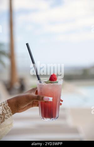 Hand einer schwarzen Frau mit perfekt gepflegten Nägeln, die ein hohes Glas mit einem kalten Getränk, einem Cocktail oder einem Mocktail im Freien hält Stockfoto