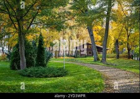 Herbstpark mit Wanderweg, entlang des Seeufers und Holzhütte mit großen Fenstern. Stockfoto