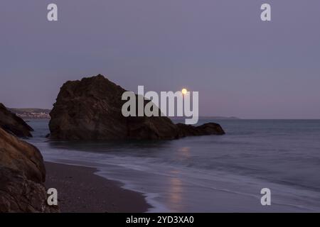 Mondaufgang durch und über Felsen am Ende des Plaidy Beach in der Nähe von Looe, Cornwall, Großbritannien, 17. September 2024, Nacht vor Super Harvest Moon, Corn Moon Stockfoto