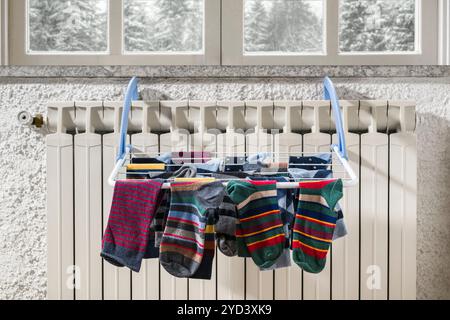 Farbenfrohe Socken hängen an der Wäscheleine und trocknen im Winter auf dem Heizkörper. Stockfoto