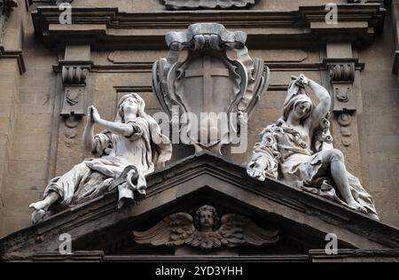 Statuen der Hoffnung und der Armut saßen beiderseits der Wappen des Theatinischen Ordens über der zentralen Tür an der Fassade des Santi Mi Stockfoto