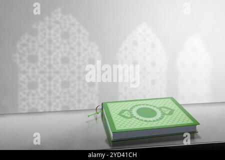 Das heilige Buch von Al Quran, das auf einem Tisch sitzt, mit einem Schatten von Moscheefenstern an der Wand. Muslimisches heiliges Buch. Konzept der islamischen Religion, Ramadan kareem, Stockfoto