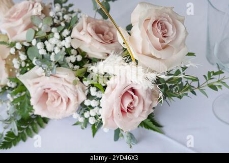 Elegantes Herzstück auf einem Esstisch, Blumenarrangements mit weichen rosa Rosen, ergänzt durch grüne und weiße Füllstoffe Stockfoto