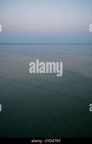 Grüne stille Gewässer des Lake Michigan mit Land am Horizont in der Abenddämmerung Stockfoto