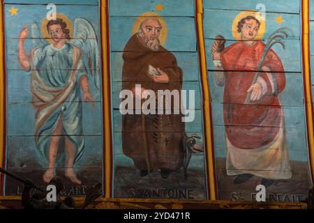 Mitte der 1800er Jahre Gemälde auf holzgetäfeltem Deckengewölbe der Kirche Saint Nonne, Dirinon, Finistère, Bretagne, Frankreich. Von links: Schutzengel, der Heilige Antonius von Padua (St. Antoine) mit dem Teufel zu seinen Füßen und der Heilige Perfect von Cordoba (St. Parfait), der das Märtyrersymbol eines Palmenwedes hält. Stockfoto