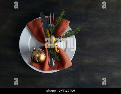 Goldene Weihnachtskugel, Serviette und Weihnachtsbaumzweig auf weißem Teller Stockfoto