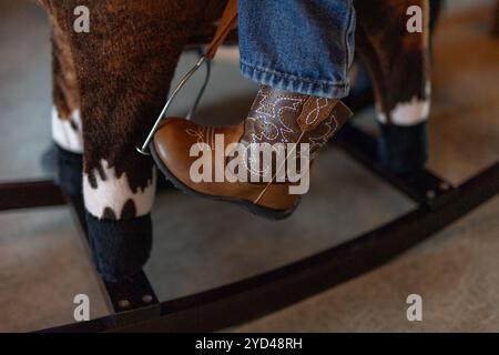 Cowboystiefel eines Kindes in einem Bügel auf einem Spielzeugpferd, Nahaufnahme Stockfoto