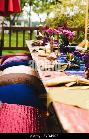 Tisch im böhmischen Stil mit Kissen, Teekanne und Blumendekor. Stockfoto