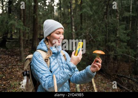 Frau, die mit Technologie Pilze in einem Wald identifiziert Stockfoto