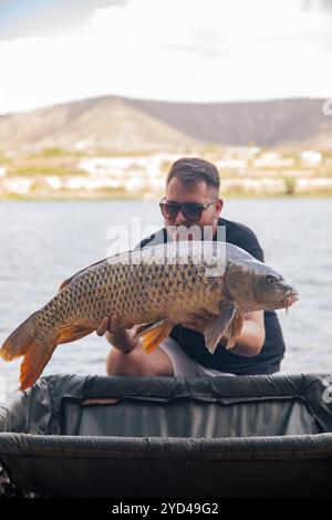 Ein kleiner Junge, der einen Karpfen zeigt, den er gerade gefangen hat Stockfoto