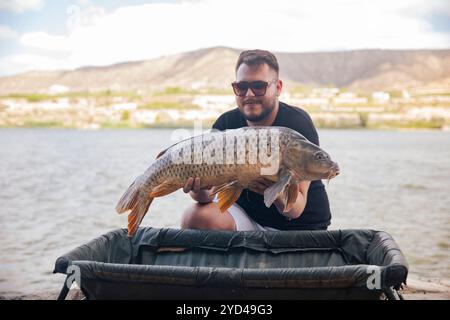 Ein kleiner Junge, der einen Karpfen zeigt, den er gerade gefangen hat Stockfoto