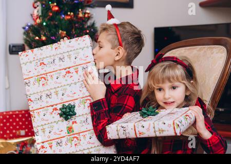 Bruder und Schwester in weihnachtlichen Outfits, die Geschenke in Händen halten Stockfoto