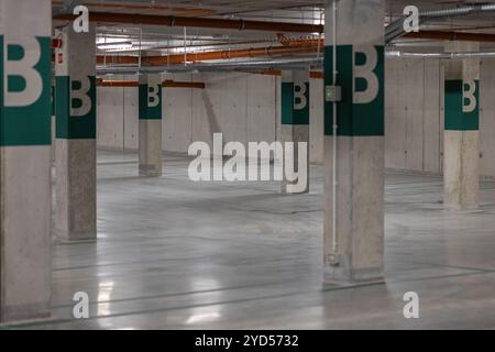 Moderner, geräumiger und leerer Parkplatz mit industriellen Designelementen wie freiliegenden Rohren und glattem Betonboden Stockfoto