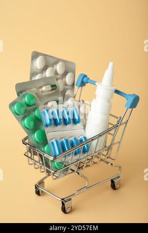 Einkaufswagen mit Pillen auf beigefarbenem Hintergrund. Der Begriff der Medizin und der Arzneimittelverkauf. Draufsicht Stockfoto