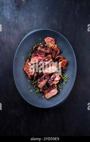 Traditionelles gebratenes Wildhasenfilet mit Pflaumen, Preiselbeeren und Speck in Rotwein-Jus serviert als Blick von oben auf dem nordischen Design-Teller mit Kopierraum Stockfoto