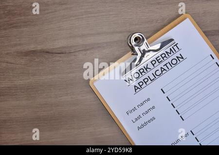 Draufsicht der Zwischenablage aus Papier mit dem Formular für den Antrag auf Arbeitserlaubnis auf Holztisch. Kopierbereich für Text. Stockfoto