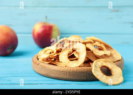 Getrocknete Apfelchips in Holzplatte auf blauem Hintergrund. Draufsicht Stockfoto