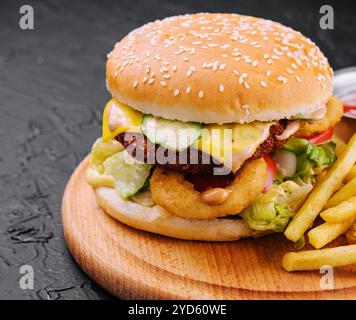 Saftiger Burger mit Zwiebelringen und Pommes frites Stockfoto