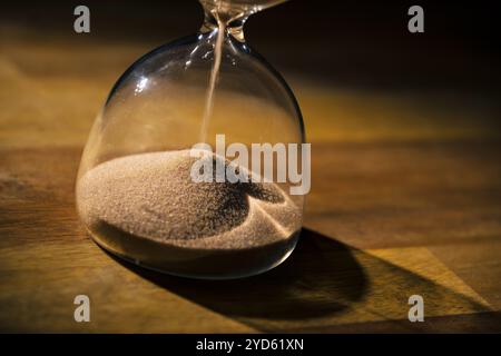 Goldene, glitzernde Sandkörner auf dem Haufen, undichter Sand aus Sanduhr, Makroaufnahme. Zeitverlaufskonzept. Stockfoto