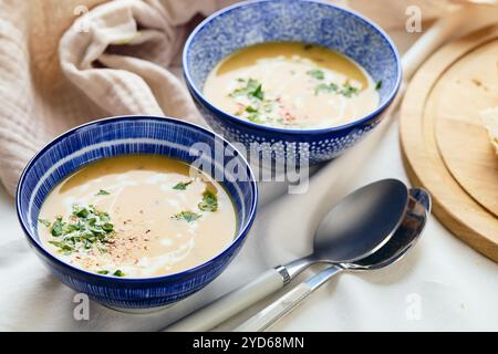 Zwei Schüsseln cremige Kartoffelsuppe, Löffel, Serviette und hölzerne Schneidebrett mit einem Laib Brot und geschnittenen Stücken. Die Fläche des Stockfoto