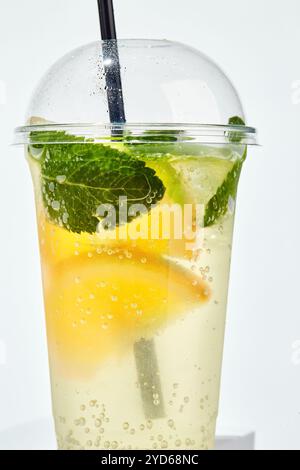 Limonade mit Zitrone, Orange, Limette und Minze in transparentem Kunststoffglas auf weißem Hintergrund Stockfoto