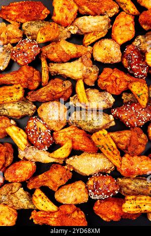 Frittierte knusprige Chicken Wings mit verschiedenen Geschmacksrichtungen und Saucen auf schwarzem Hintergrund Stockfoto