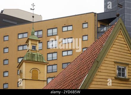 Holzhaus mit gekacheltem Dach und Türmchen mit Wetterfahne vor dem Hintergrund moderner Gebäude in Tallinn, Estland Stockfoto