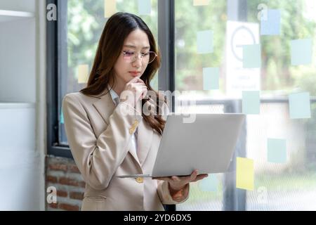 Glückliche junge Geschäftsfrau, die allein im Büro an ihrem Projekt arbeitet Stockfoto