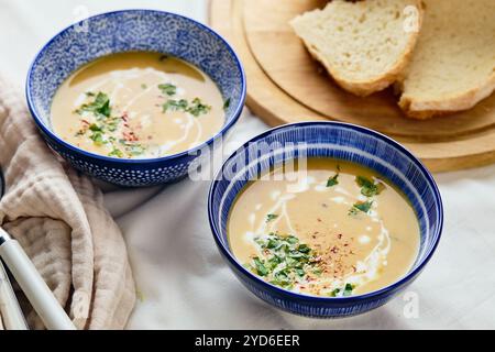 Zwei Schüsseln cremige Kartoffelsuppe, Löffel, Serviette und hölzerne Schneidebrett mit einem Laib Brot und geschnittenen Stücken. Die Fläche des Stockfoto