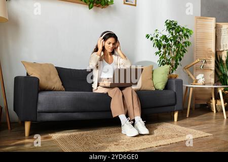 Die Frau sitzt leise mit anliegenden Kopfhörern, konzentriert sich auf ihren Laptop und sorgt für eine ruhige Atmosphäre. Stockfoto