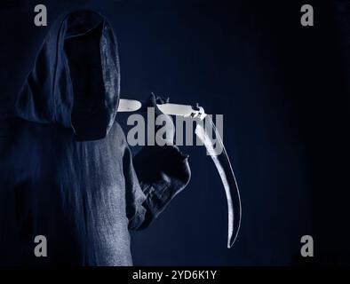 Der Tod hält eine alte Sense scharfe Klinge auf Schultern des Todes in blauer Dunkelheit Angst Stockfoto