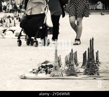 Eiffelturm Statuetten zum Verkauf im Tuileriengarten in der Nähe des Louvre Museum und Figuren von Touristen im Hintergrund. Schwarzweißfoto. Stockfoto