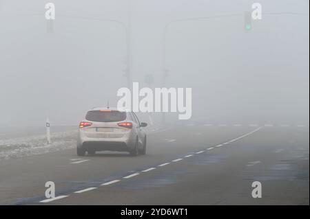 Autos im Nebel. Schlechtes Winterwetter und gefährlicher Autoverkehr auf der Straße. Leichte Fahrzeuge im Nebel. Stockfoto