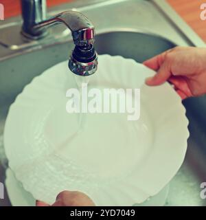 Hand abwaschen. Hand mit Schwamm und Waschbecken in der Küche Waschen schmutzige Geschirr - Teller. Stockfoto