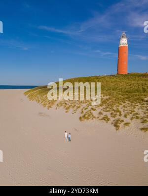 Ein Blick aus der Vogelperspektive auf einen majestätischen Leuchtturm am Strand von Texel, Niederlande, umgeben von goldenem Sand und dem Sooothin Stockfoto