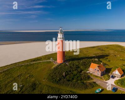 Ein majestätischer Leuchtturm steht hoch an einem Sandstrand und überblickt das endlose Meer mit seinem leuchtenden Leuchtfeuer Stockfoto