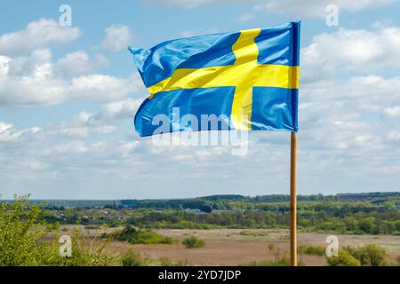 Die Nationalflagge Schwedens winkt im Wind am Himmel mit Wolken. Der Begriff der internationalen Beziehungen. Stockfoto