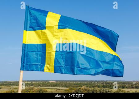 Die Nationalflagge Schwedens winkt im Wind am Himmel mit Wolken. Der Begriff der internationalen Beziehungen. Stockfoto