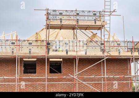 Blick auf ein neu erbautes Haus auf einer britischen Baustelle mit Gerüsten. Dachkonstruktion. Stockfoto