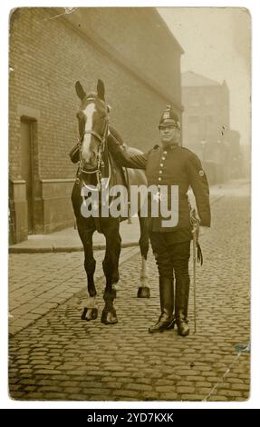 Ursprünglich aus den frühen 1900er Jahren stammende Postkarte eines Polizisten in Uniform, der stolz neben seinem Pferd stand, Großbritannien um 1910 Stockfoto